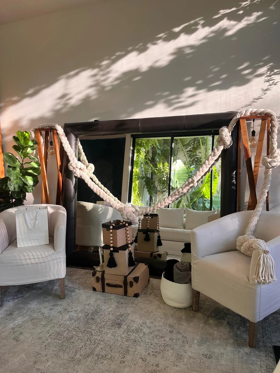 Composición de trenzas claras que enmarca una sala con sillones blancos y ventanas hacia el jardín.