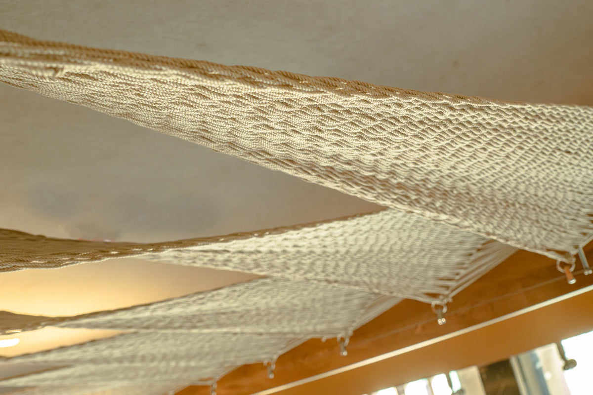 Detalle de la trama clara del techo, con luz cálida entre las superficies tejidas.