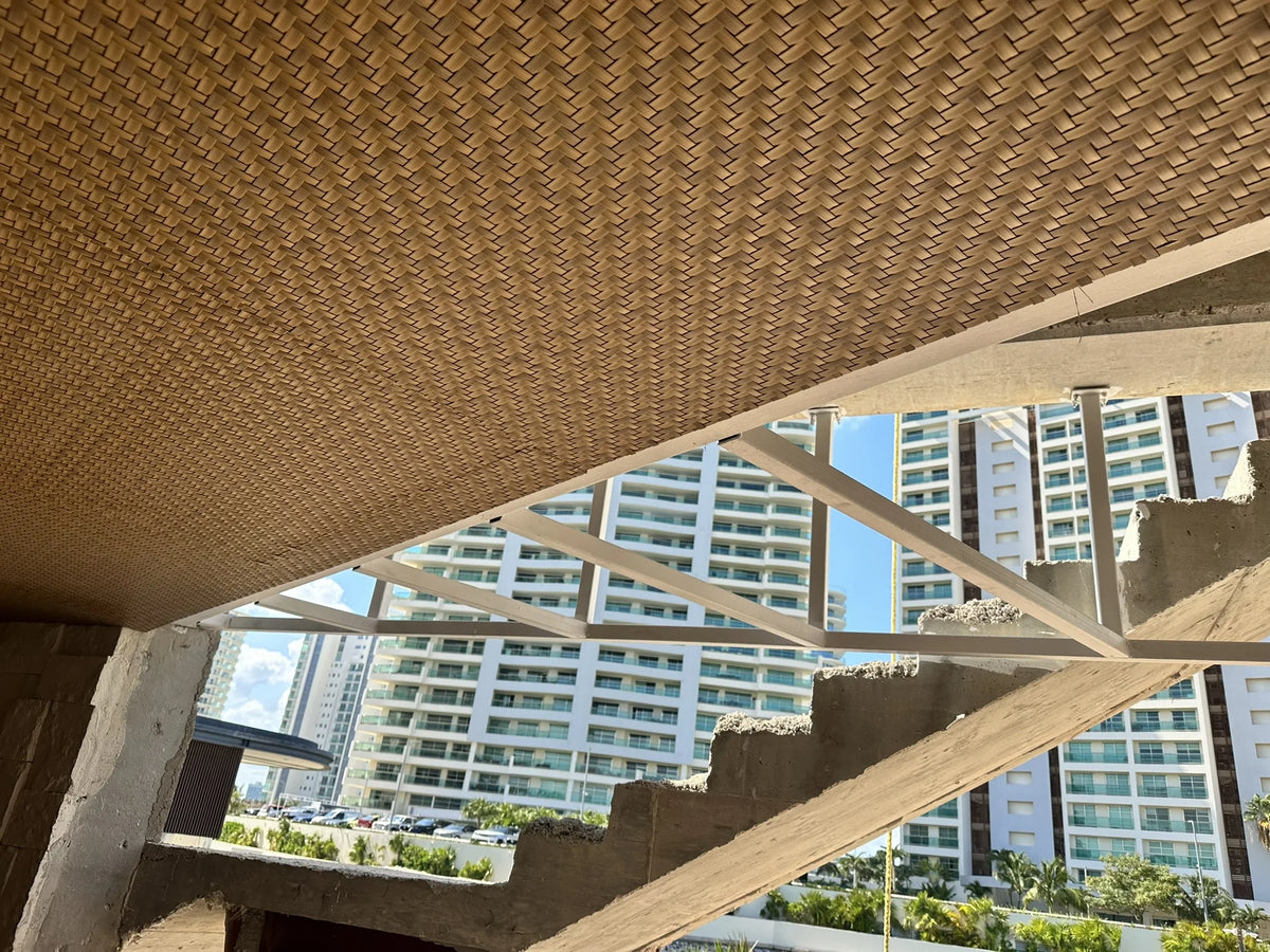 Detalle del plafón tejido durante su instalación, junto a una estructura blanca y una escalera de concreto.